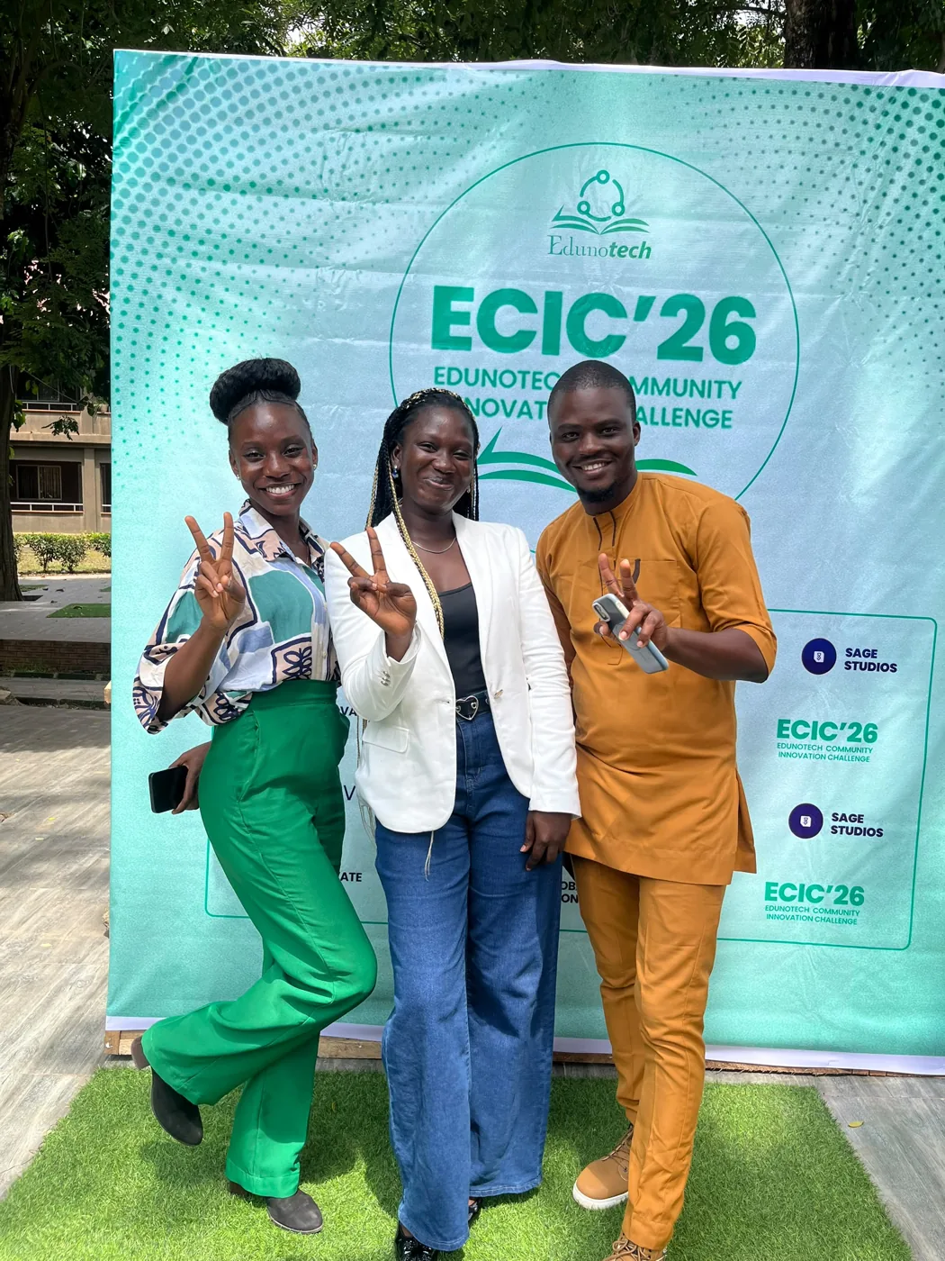 Anjola with two others in front of the ECIC 26 banner